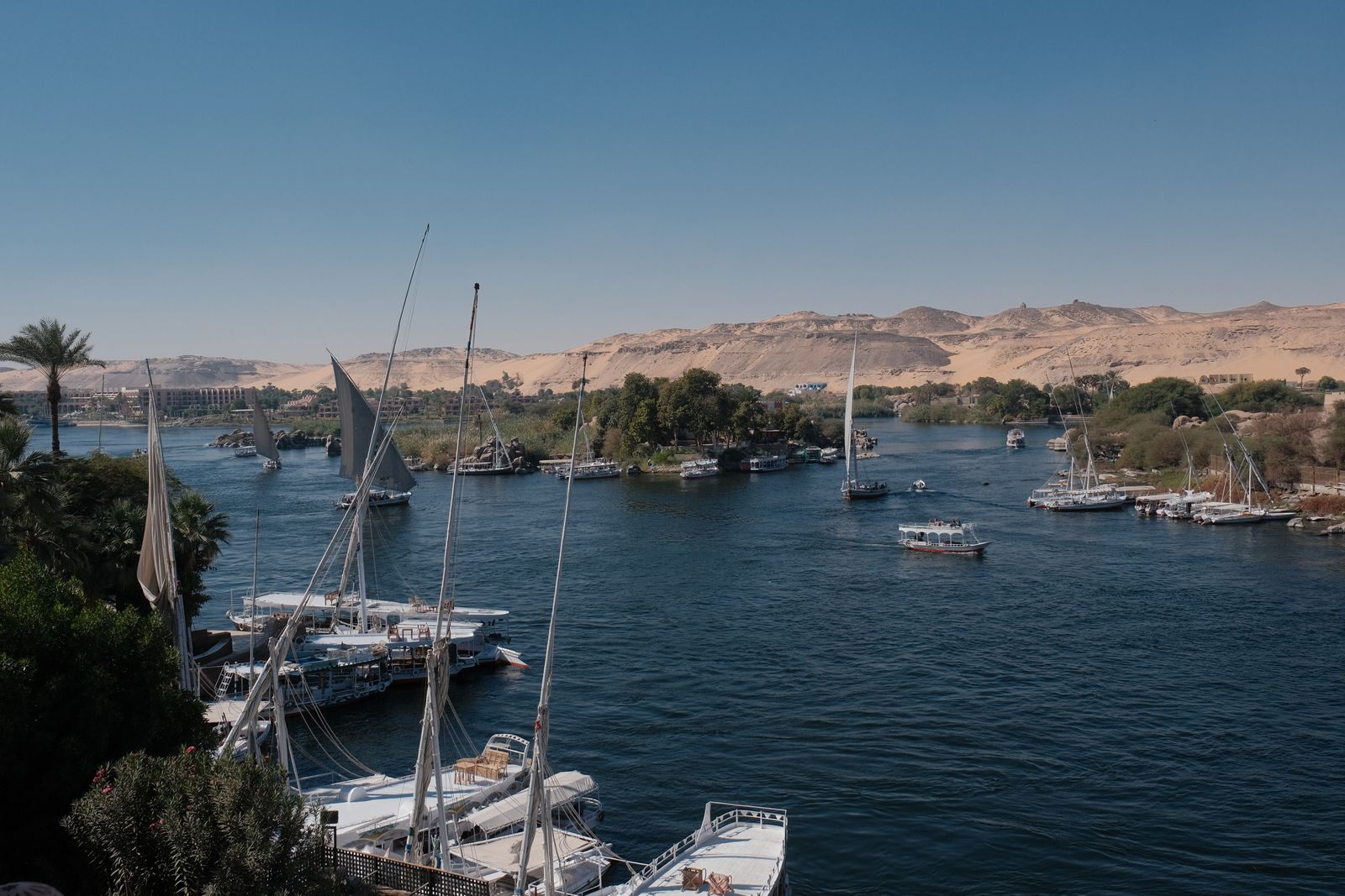 Sailboats moored on the Nile at Aswan with desert dunes beyond